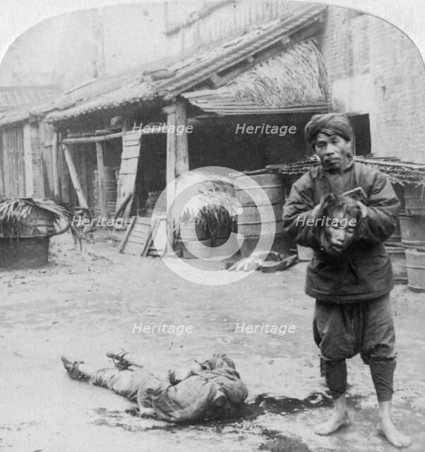 'The grim executioner taking the labled head to exhibit a warning', Canton, China, 1900.  Artist: Underwood & Underwood