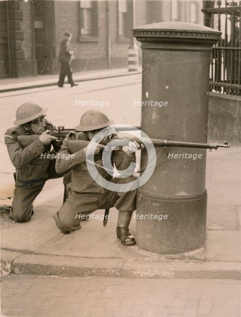 The Home Guard find cover behind a pillar box during a enemy engagement rehearsal, 1941. Artist: Unknown