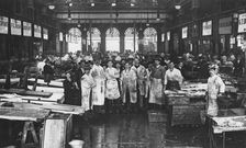 The interior of Billingsgate Market showing fishmongers and their stalls, London, c1918
