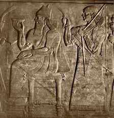 The king, Ashurnasirpal is seated between two attendants