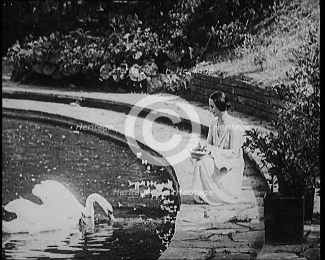 The Russian Ballerina Anna Pavlovna Pavlova Feeding Swans by a Pond, 1920. Creator: British Pathe Ltd.