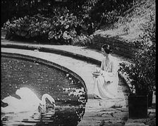 The Russian Ballerina Anna Pavlovna Pavlova Feeding Swans by a Pond, 1920. Creator: British Pathe Ltd