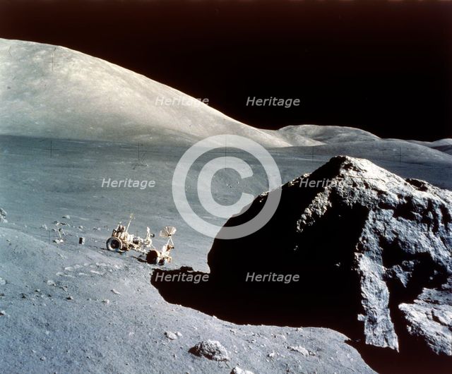The Rover is dwarfed by a giant rock on the lunar surface, Apollo 17 mission, December 1972. Creator: NASA.