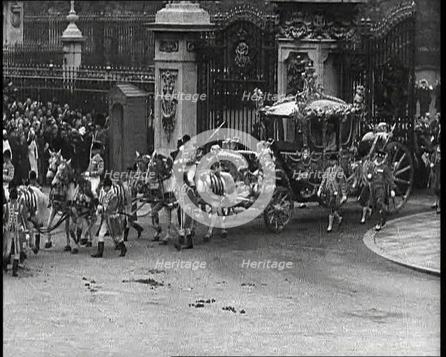 The Royal Coach, Horses, and Procession Filing Out of the Gates at the Front of Buckingham..., 1937. Creator: British Pathe Ltd.
