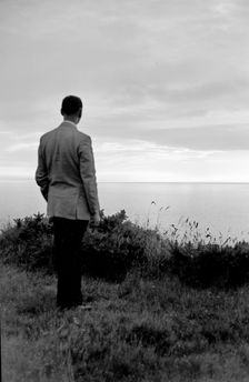 The silhouette of a man standing on a cliff top watching the sunset over the sea, c1945-c1965. Artist: SW Rawlings