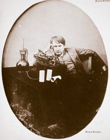 Thomas Alva Edison, American inventor, sitting beside his improved machine, 1889