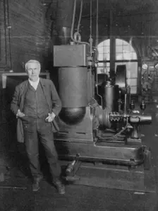 Thomas Alva Edison, American inventor, with his first dynamo for producing electric light, 1880s. Creator: Unknown