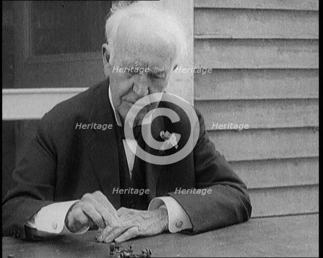 Thomas Edison Sitting at an Outside Desk and Operating a Morse Code Sender, 1921. Creator: British Pathe Ltd.