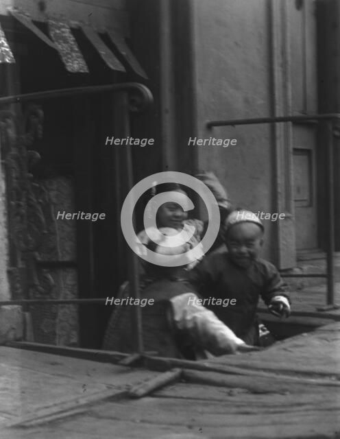 Three children in front of a cellar door, Chinatown, San Francisco, between 1896 and 1906. Creator: Arnold Genthe.