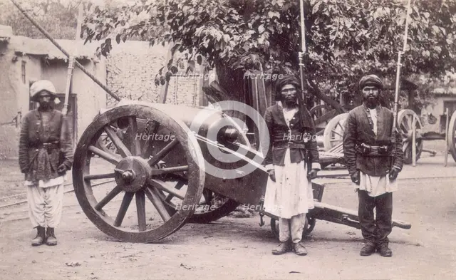 Three Afghan soldiers standing next to a cannon, Afghanistan, 1880s. Creator: Unknown.