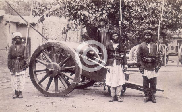 Three Afghan soldiers standing next to a cannon, Afghanistan, 1880s. Creator: Unknown.