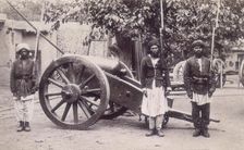 Three Afghan soldiers standing next to a cannon, Afghanistan, 1880s. Creator: Unknown