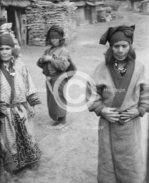Three Ainu women outside in the village lane, 1908. Creator: Arnold Genthe.