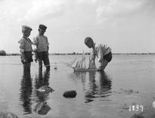 Three boys playing with a model sailing ship, 1897