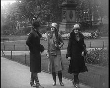 Three Female Civilians Wearing Glamorous Outfits and Long Boots Walking on a Park, 1920. Creator: British Pathe Ltd