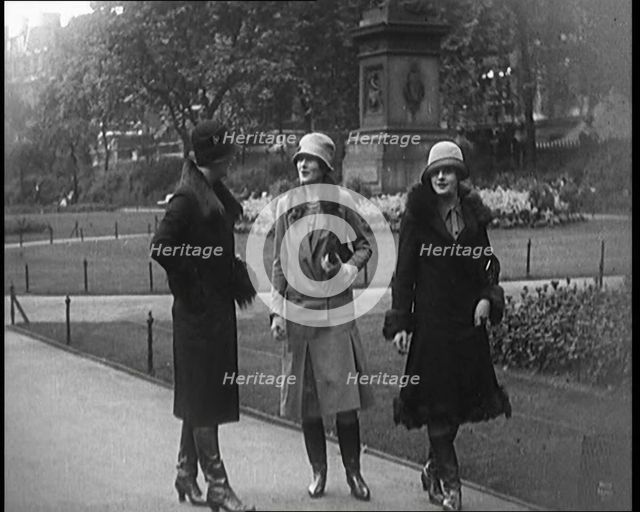 Three Female Civilians Wearing Glamorous Outfits and Long Boots Walking on a Park, 1920. Creator: British Pathe Ltd.