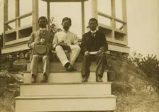 Three Japanese men, possibly journalists, seated on the steps of a gazebo, 1905. Creator: Unknown