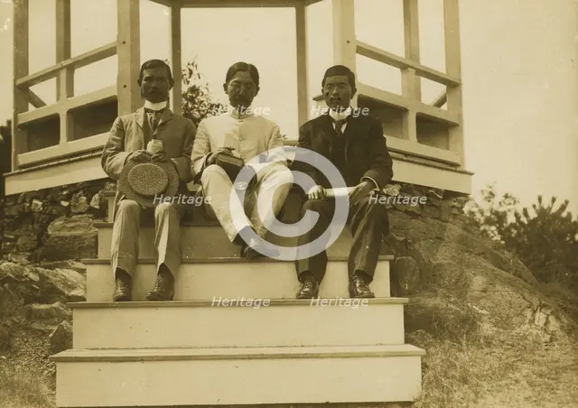 Three Japanese men, possibly journalists, seated on the steps of a gazebo, 1905. Creator: Unknown.