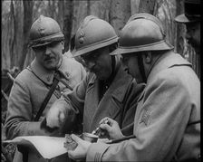Three Male French Soldiers Standing in a Wood Looking at a Map, 1924. Creator: British Pathe Ltd