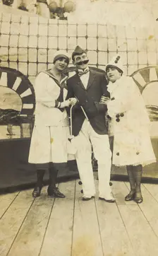 Three sailors, two in drag wearing pierrette costumes, pose on deck, c1910s. Creator: Unknown