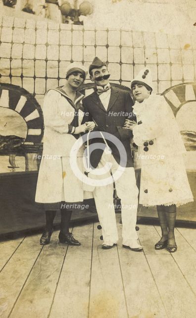 Three sailors, two in drag wearing pierrette costumes, pose on deck, c1910s. Creator: Unknown.