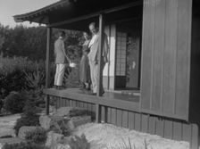Three people standing on the porch of a Japanese-style building in a garden... A.W. Bahr, c1917-1934 Creator: Arnold Genthe