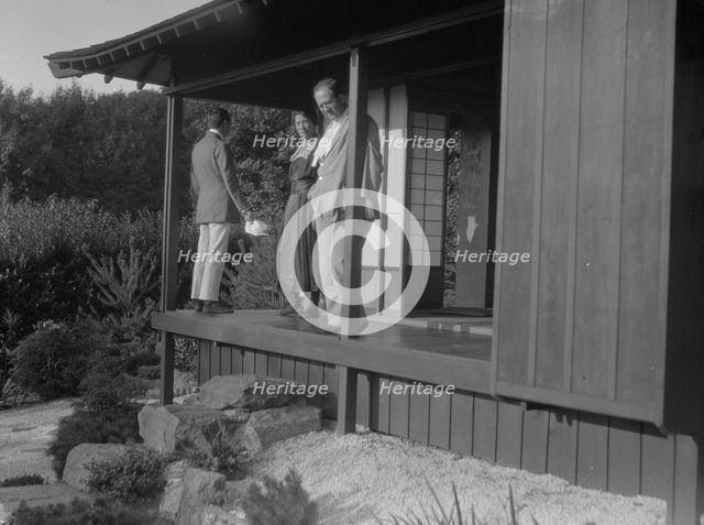Three people standing on the porch of a Japanese-style building in a garden... A.W. Bahr, c1917-1934 Creator: Arnold Genthe.