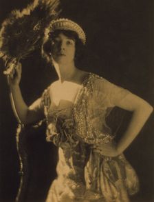 Three-quarter length portrait of Gertrude Vanderbilt Whitney...holding a peacock feather fan, c1916. Creator: Adolph de Meyer