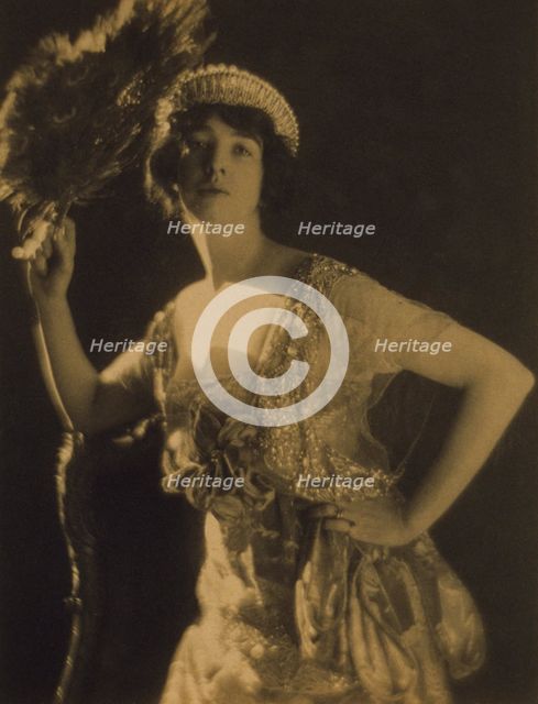 Three-quarter length portrait of Gertrude Vanderbilt Whitney...holding a peacock feather fan, c1916. Creator: Adolph de Meyer.