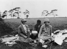 Three women having a picnic in a field, (1920s?)