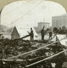 True grit - Barber painting sign on tent stretched on sidewalk of former place 1906. Creator: Unknown