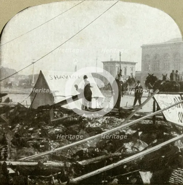 'True grit - Barber painting sign on tent stretched on sidewalk of former place', 1906.  Creator: Unknown.