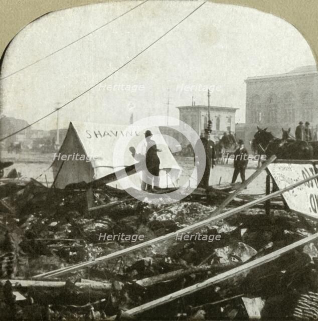 'True grit - Barber painting sign on tent stretched on sidewalk of former place', 1906.  Creator: Unknown.