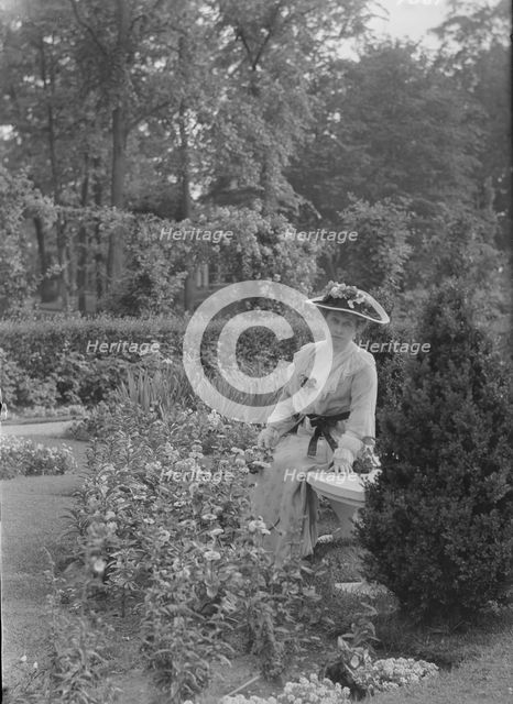 Truesdale, W., Mrs., standing in a garden, 1915 July 6. Creator: Arnold Genthe.