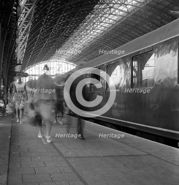Travellers walking along a platform at Centraal Station, Amsterdam, Netherlands, 1963. Artist: Michael Walters