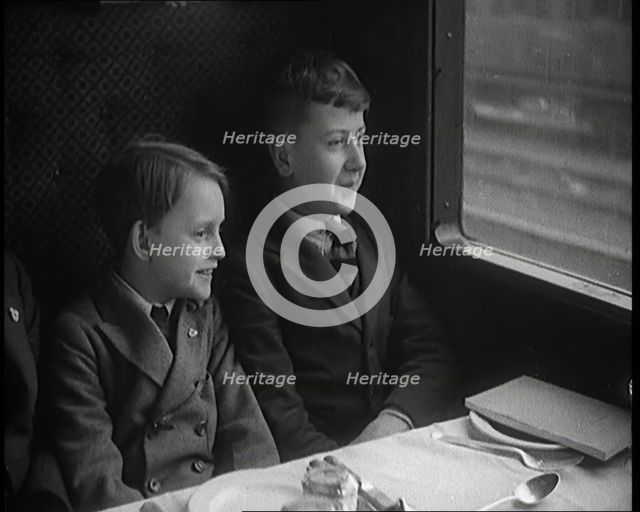 Two Male Children in a Train Carriage Sitting in Front of a Table Laid for a Meal, 1931. Creator: British Pathe Ltd.