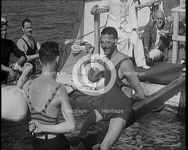 Two Male Civilians in Swim Suits Sitting on a Pole and Enjoying a Pillow Fight in Front..., 1931. Creator: British Pathe Ltd.