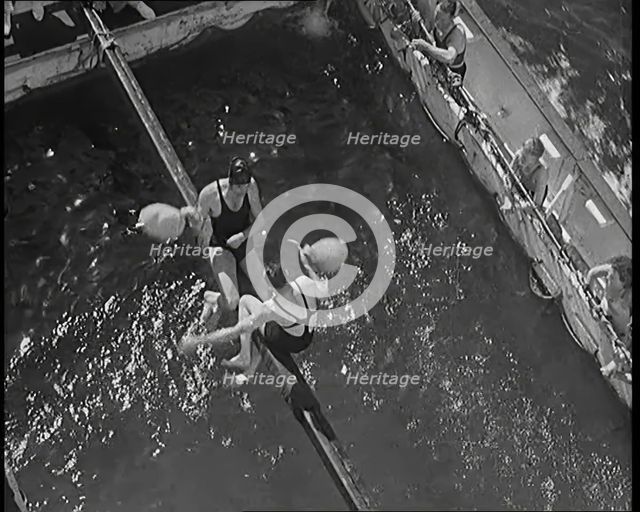 Two Male Civilians in Swim Suits Sitting on a Pole and Enjoying a Pillow Fight in Front..., 1931. Creator: British Pathe Ltd.