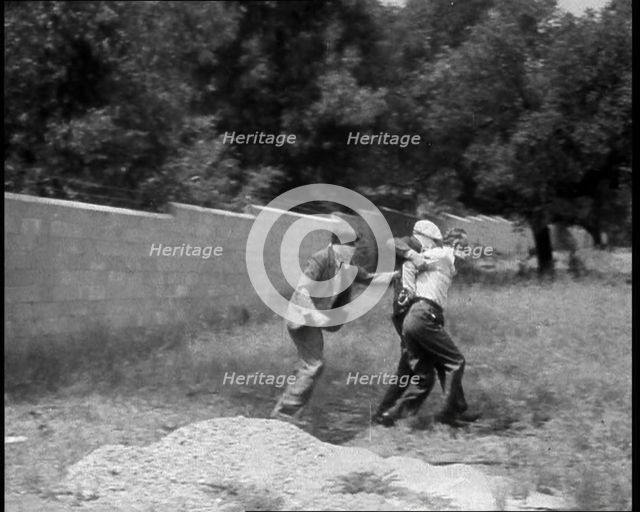 Two Male American Civilians Covering Their Faces with Handkerchiefs Carrying a Male American...1930. Creator: British Pathe Ltd.