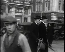 Two Male Politicians Walking Along a Busy Bridge Street Towards the Palace of Westminster, 1937. Creator: British Pathe Ltd