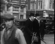 Two Male Politicians Walking Along a Busy Bridge Street Towards the Palace of Westminster, 1937. Creator: British Pathe Ltd