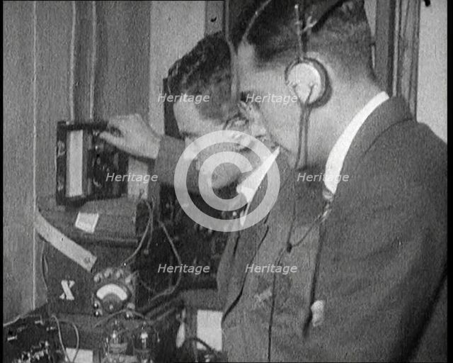 Two Men Wearing Headphones and Calibrating Wireless Equipment, 1922. Creator: British Pathe Ltd.