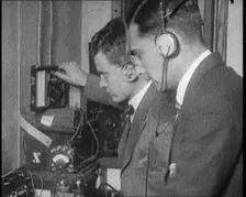Two Men Wearing Headphones and Calibrating Wireless Equipment, 1922. Creator: British Pathe Ltd