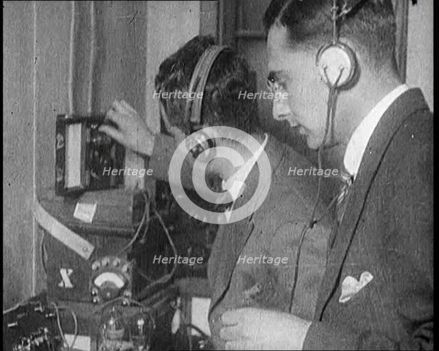 Two Men Wearing Headphones and Calibrating Wireless Equipment, 1922. Creator: British Pathe Ltd.