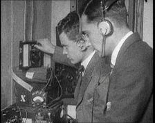 Two Men Wearing Headphones and Calibrating Wireless Equipment, 1922. Creator: British Pathe Ltd