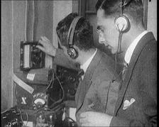 Two Men Wearing Headphones and Calibrating Wireless Equipment, 1922. Creator: British Pathe Ltd