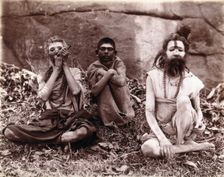 Two men and a boy sitting cross-legged on the ground surrounded by leaves; their faces... 1896/1897 Creator: Unknown