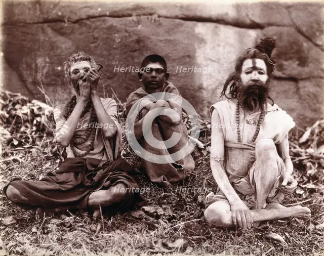 Two men and a boy sitting cross-legged on the ground surrounded by leaves; their faces...  1896/1897 Creator: Unknown.