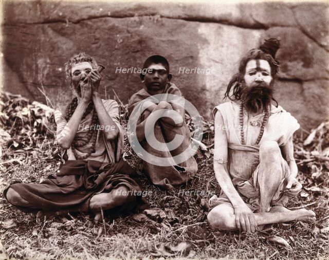 Two men and a boy sitting cross-legged on the ground surrounded by leaves; their faces...  1896/1897 Creator: Unknown.