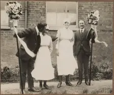 Two men holding tutti poles, with two women during the Hocktide Festival in Hungerford, 1925-35. Creator: George R Long